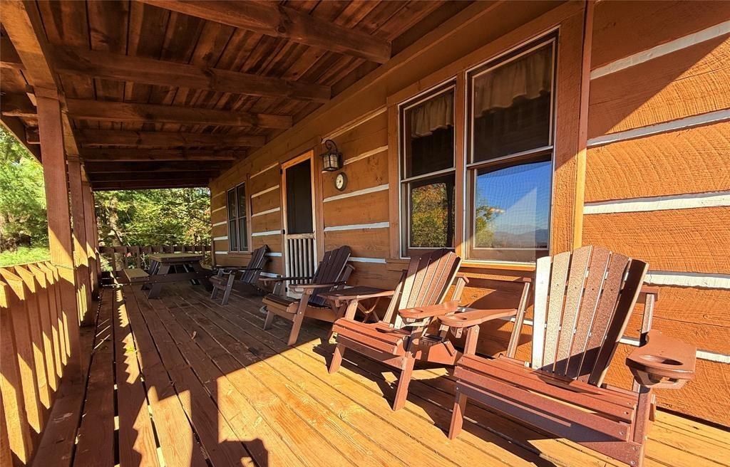 The covered porch with a picnic table, open to the mountains beyond the rail