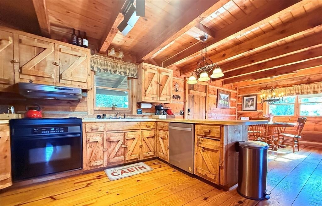 The cabin kitchen in pine cabinetry with a full range, dishwasher and bar seating